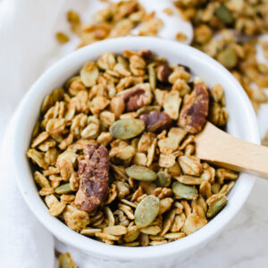 pumpkin maple granola in a ramekin with a wooden spoon