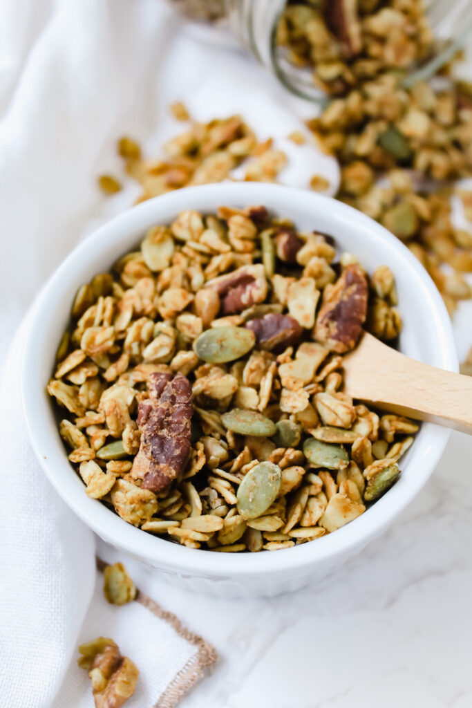 pumpkin maple granola in a ramekin with a wooden spoon