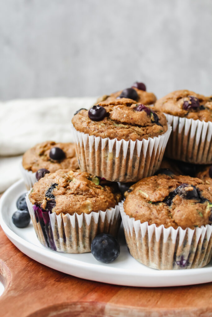 side view of the muffins stacked on a plate set on a wooden board