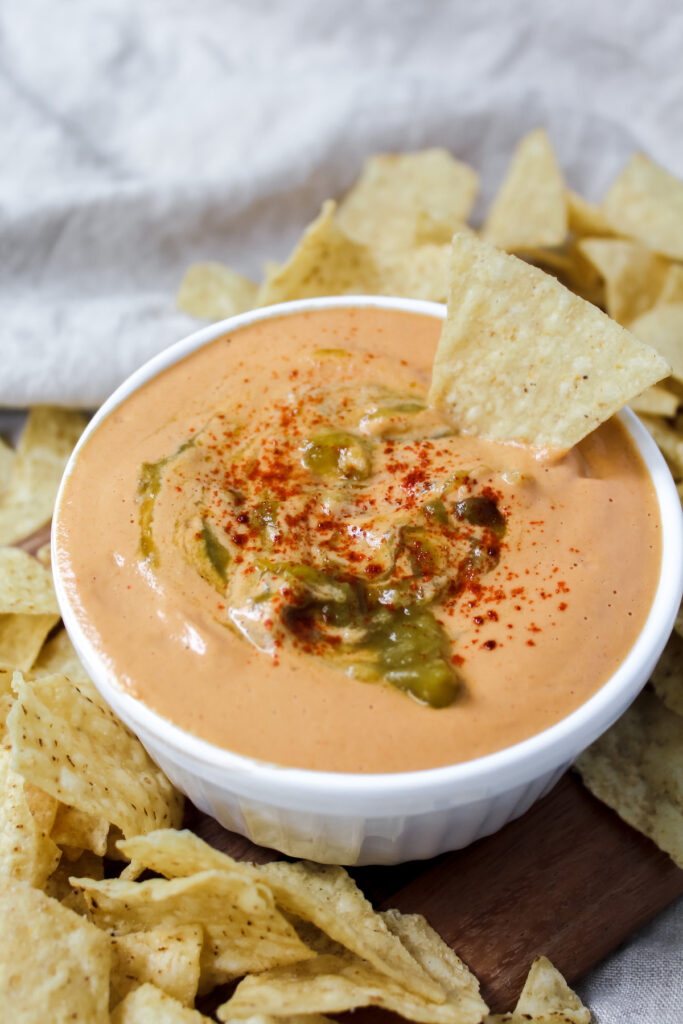 angled shot of the best vegan queso with a chip dipped in it