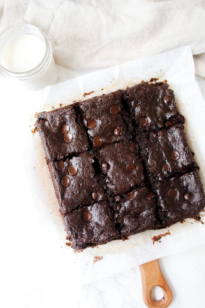 overview shot of sliced fudgy zucchini brownies with a glass of milk