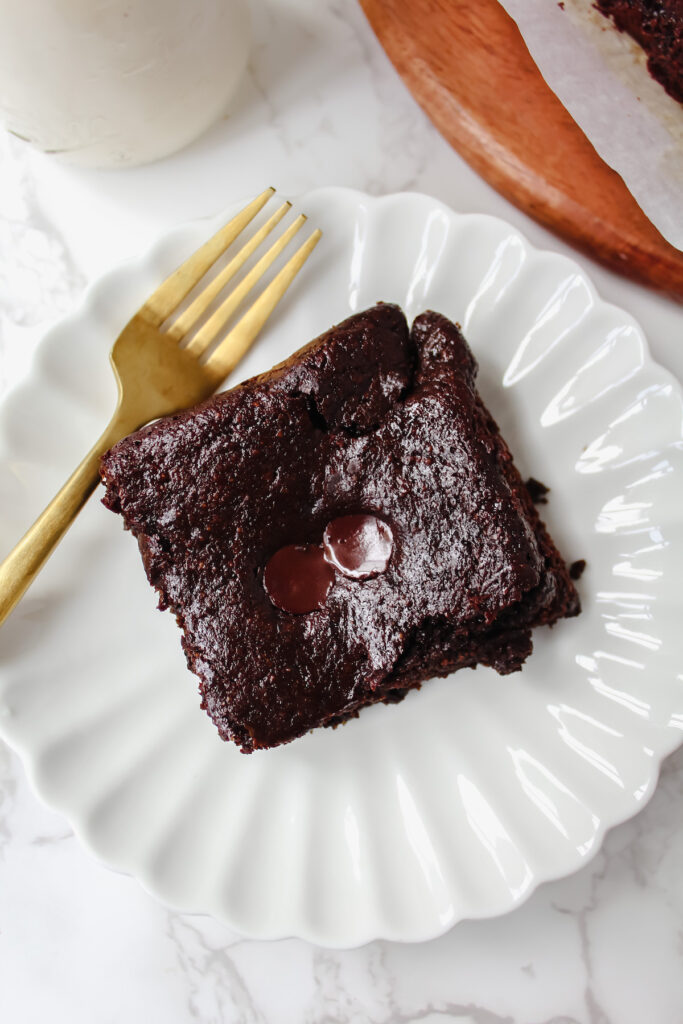 overview shot of a slice of zucchini brownie on a plate with a fork on the side