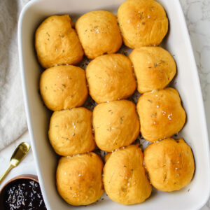 overview shot of pan of vegan sweet potato rolls with jam on the side