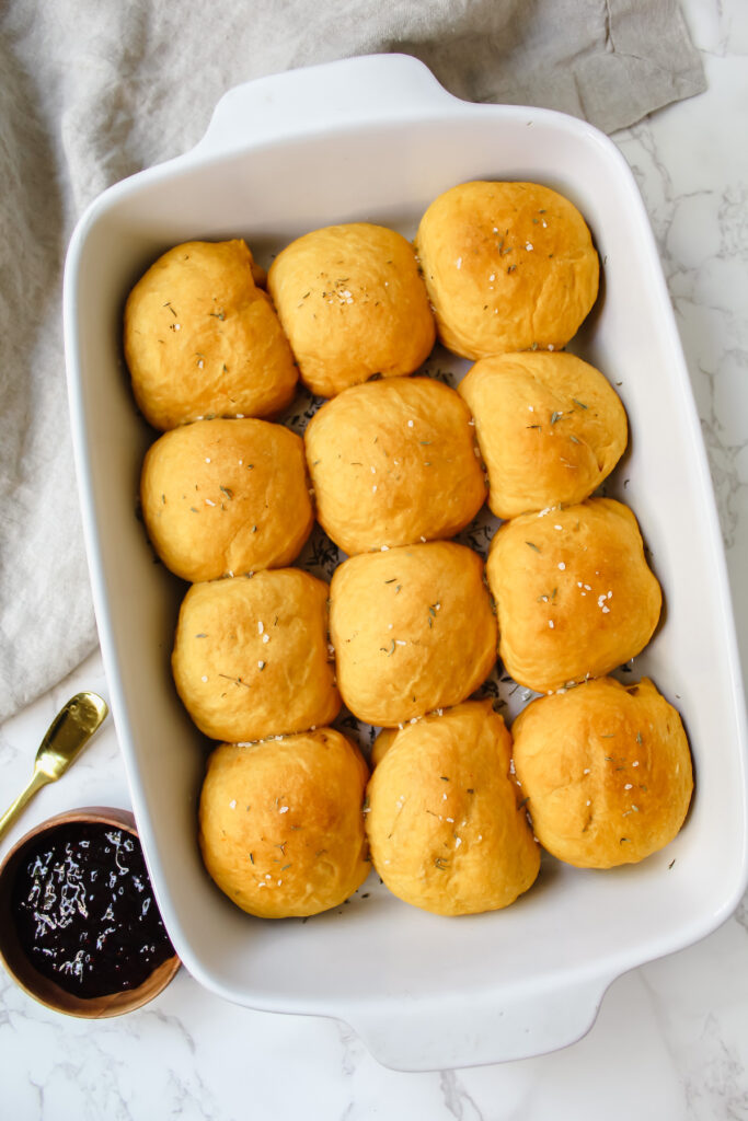 overview shot of pan of vegan sweet potato rolls with jam on the side