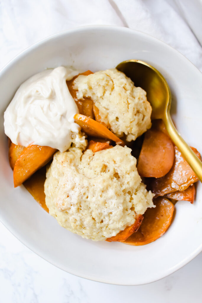 close up of cobbler in a bowl with yogurt and a spoon