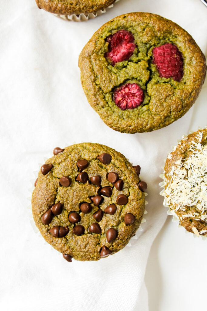 close up of healthy spinach banana muffins with chocolate chips and raspberries on top