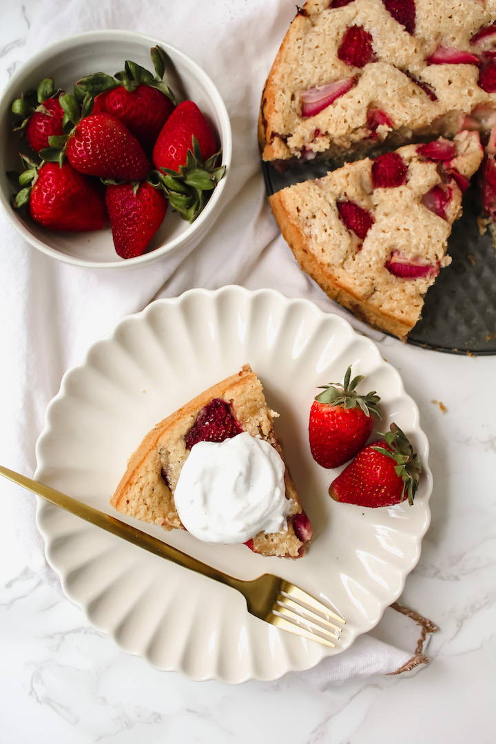 overview shot of a slice of cake with strawberries and coconut yogurt