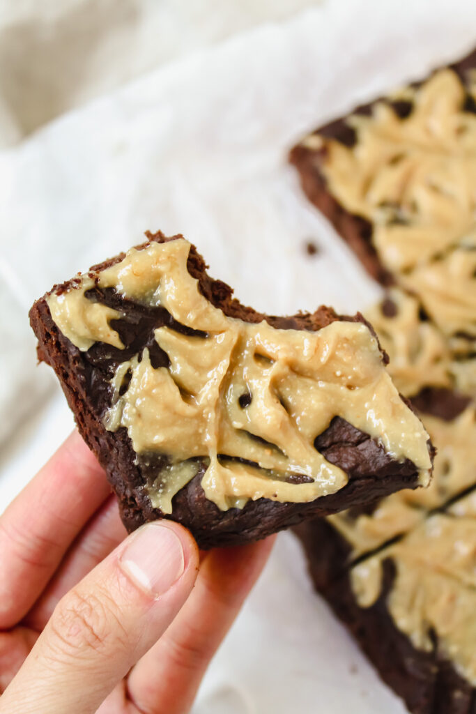 hand holding a healthy flourless pumpkin brownie with a bite taken out of the corner