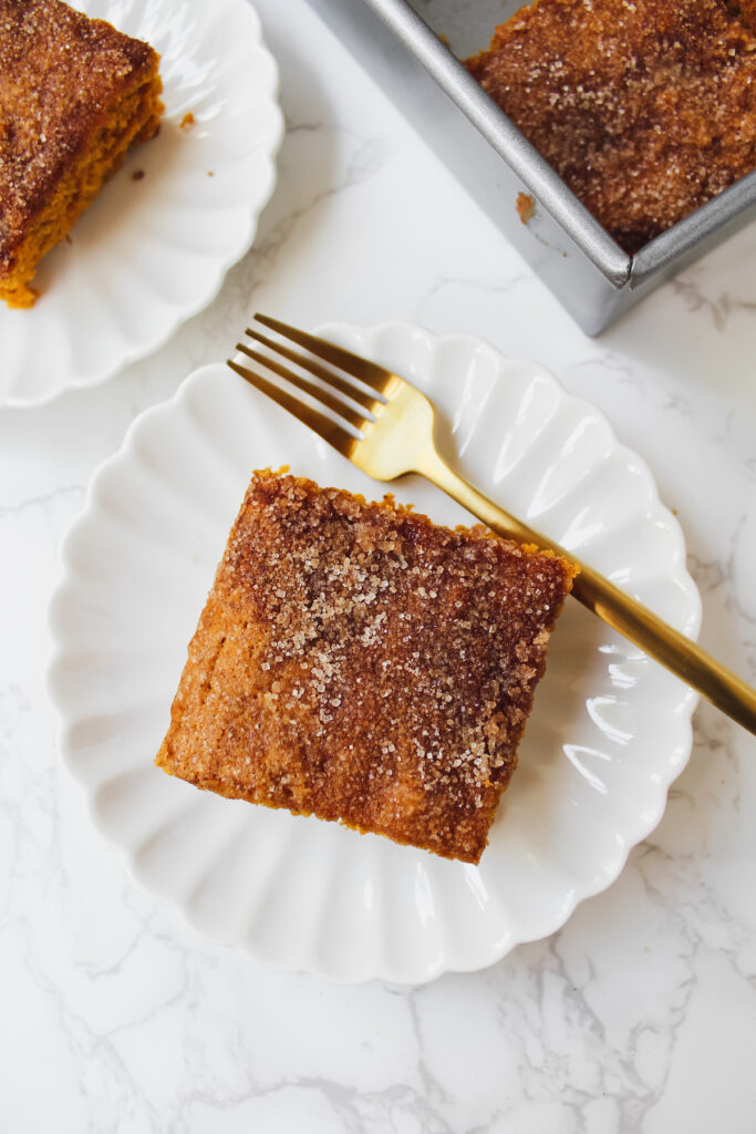 one slice of pumpkin bar on a plate with a gold fork on the side