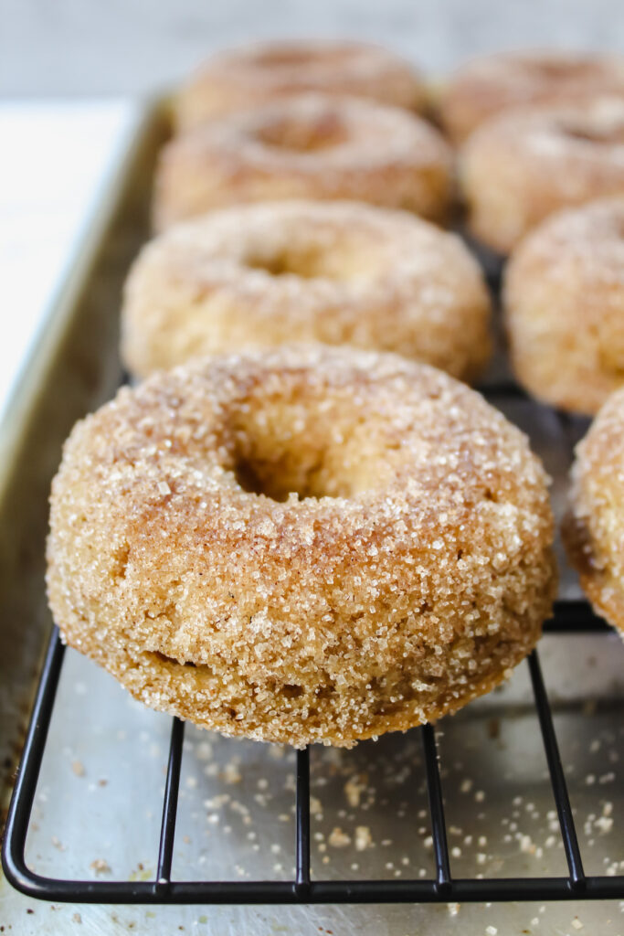 apple cider donuts lined up on a cooling rack