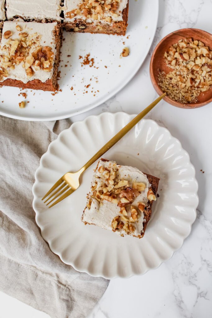 overview shot of a slice of carrot cake on a plate with a gold fork and other pieces of carrot cake