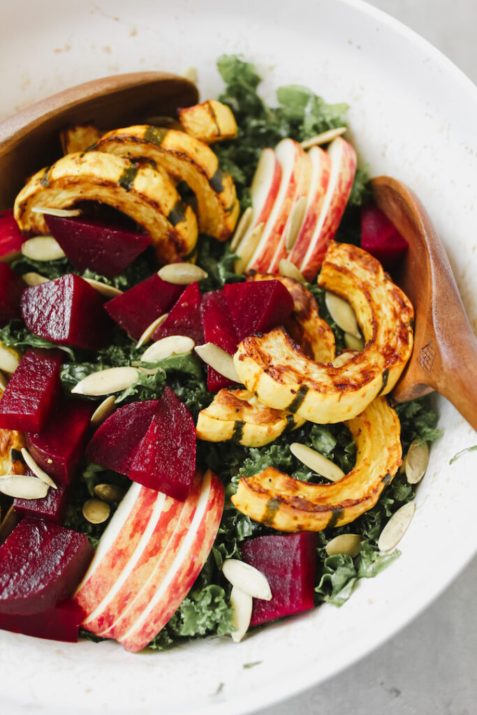 close up shot of salad with wooden salad tongs