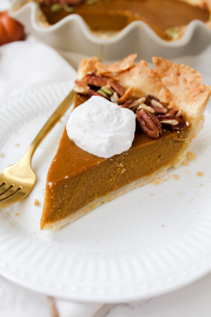 slice of vegan pumpkin pie with coconut whip on top