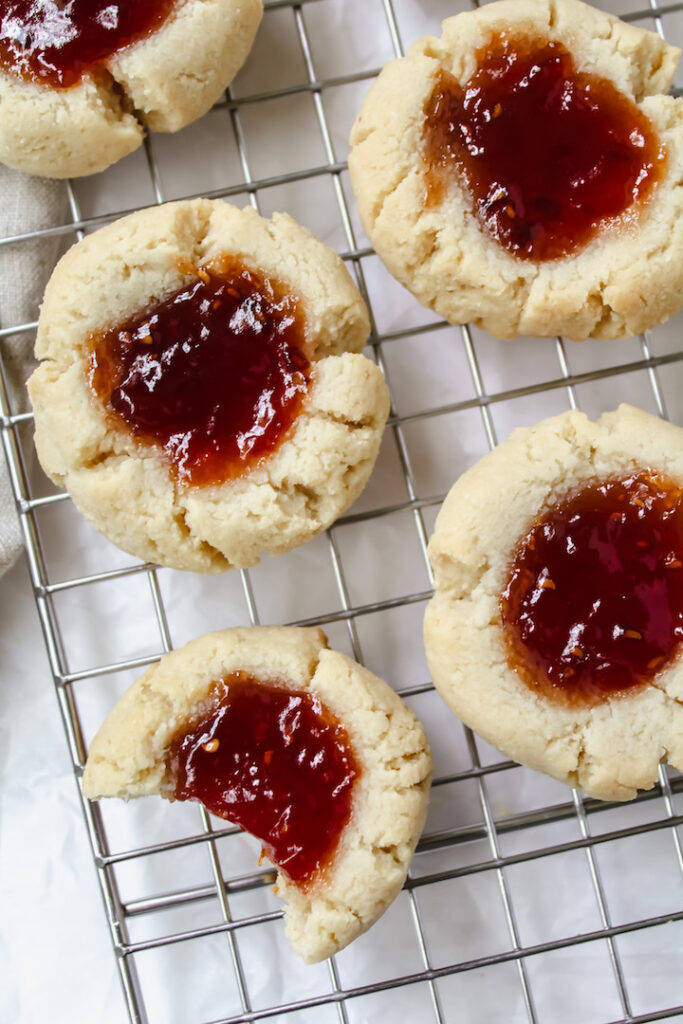 overview shot of thumbprint cookies with a bite taken out of one cookie 