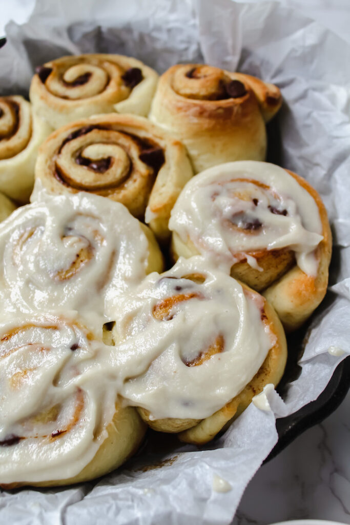 close up of some frosted vegan chocolate chip cinnamon rolls