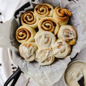 overview shot of all the cinnamon rolls with half of them frosted