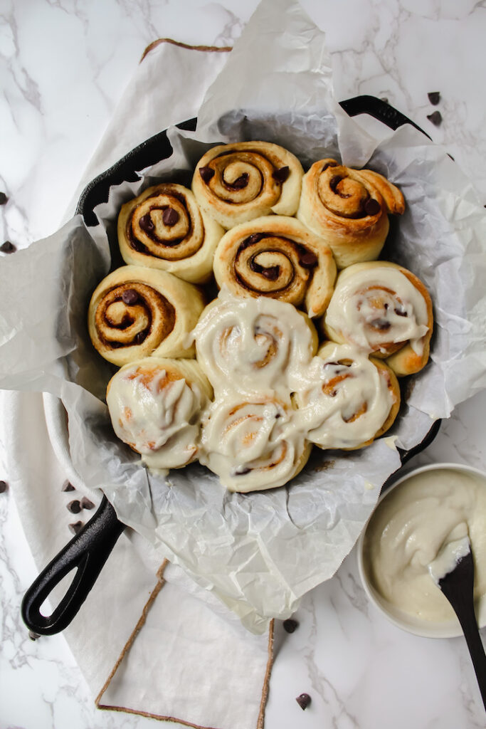 overview shot of all the cinnamon rolls with half of them frosted