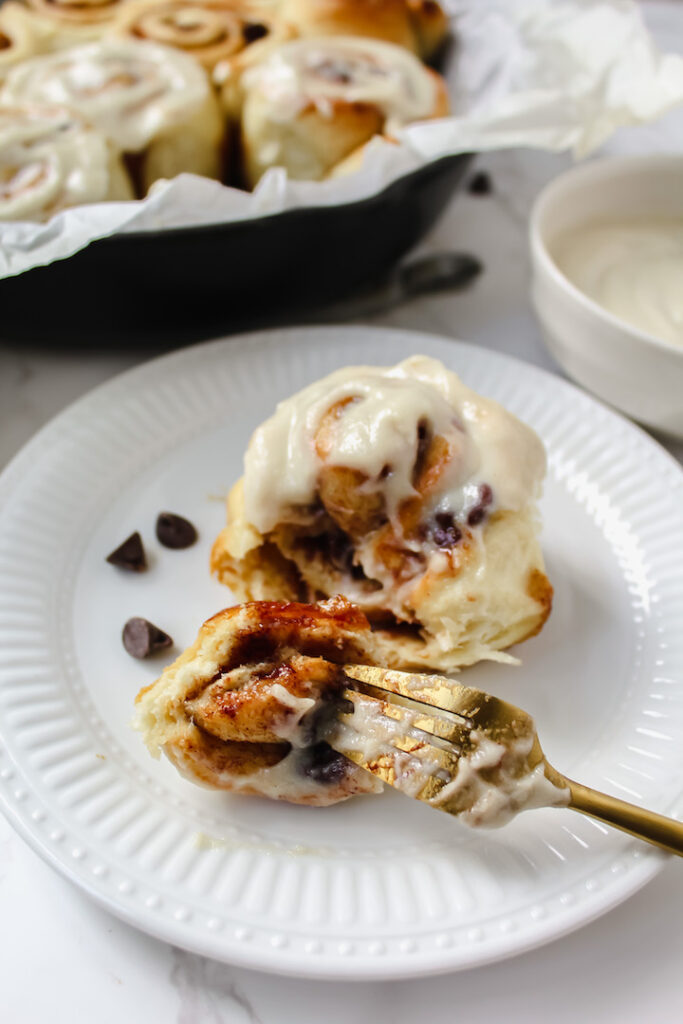 close up of a chocolate chip cinnamon roll with a bite on a fork