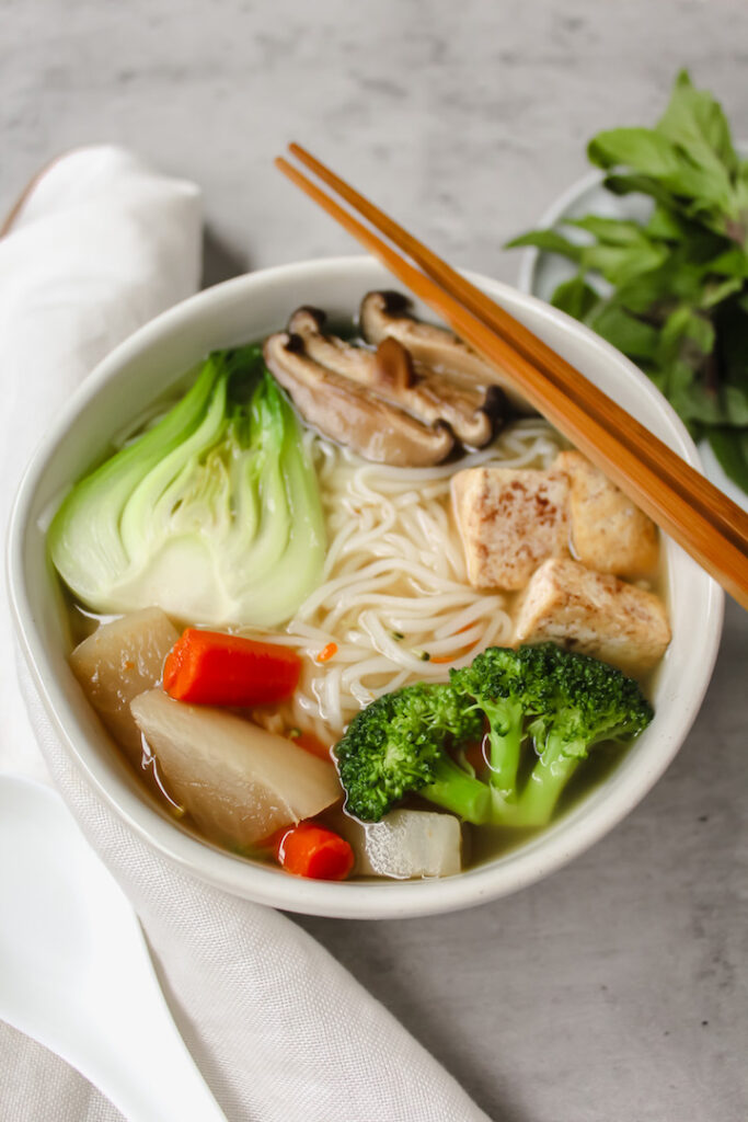 angled shot of a bowl of pho with chopsticks on top