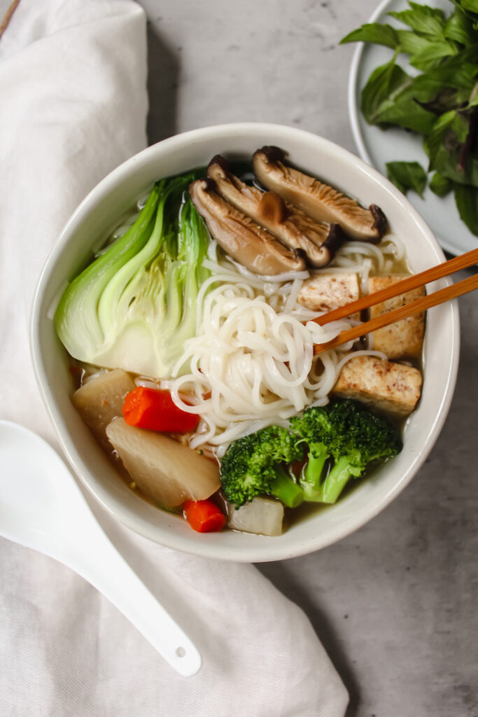 bowl of pho with noodles on chopsticks 