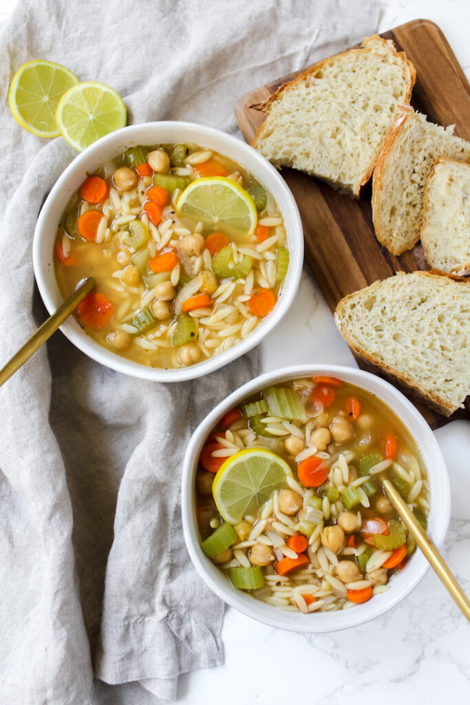 overview shot of two bowls of soup and sliced bread on the side