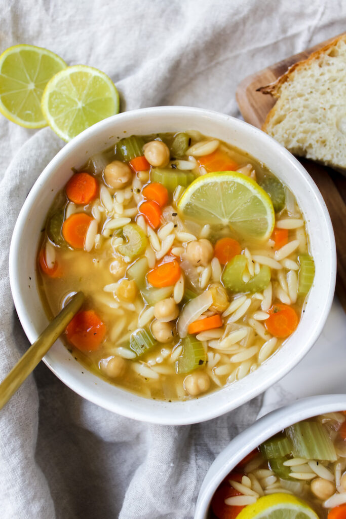 overview shot of bowl of soup with lemons on the side