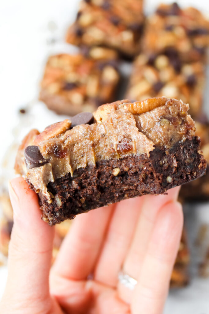 hand holding a turtle brownie with a bite taken out of it