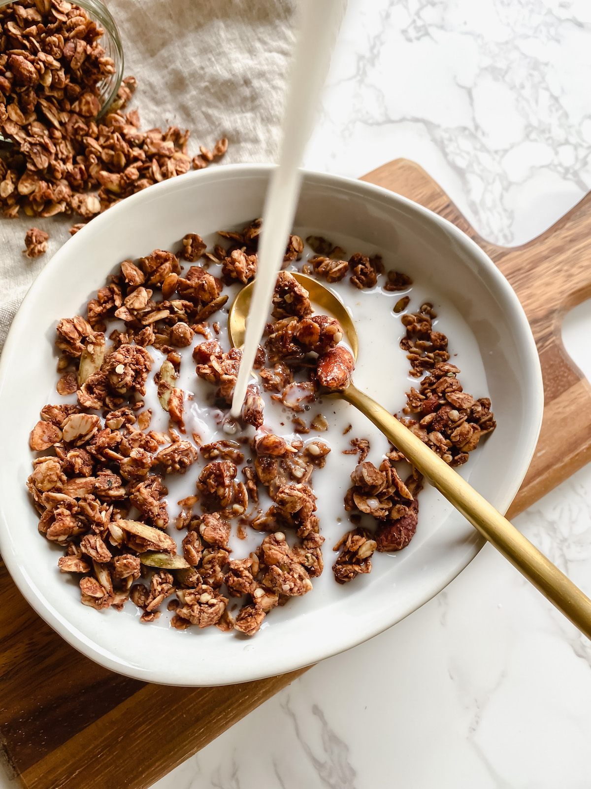 overview shot of almond milk being poured into a bowl of granola