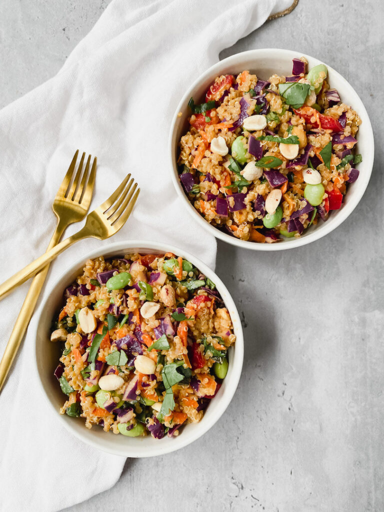 overview shot of two bowls with spicy thai quinoa salad and two gold forks on the side