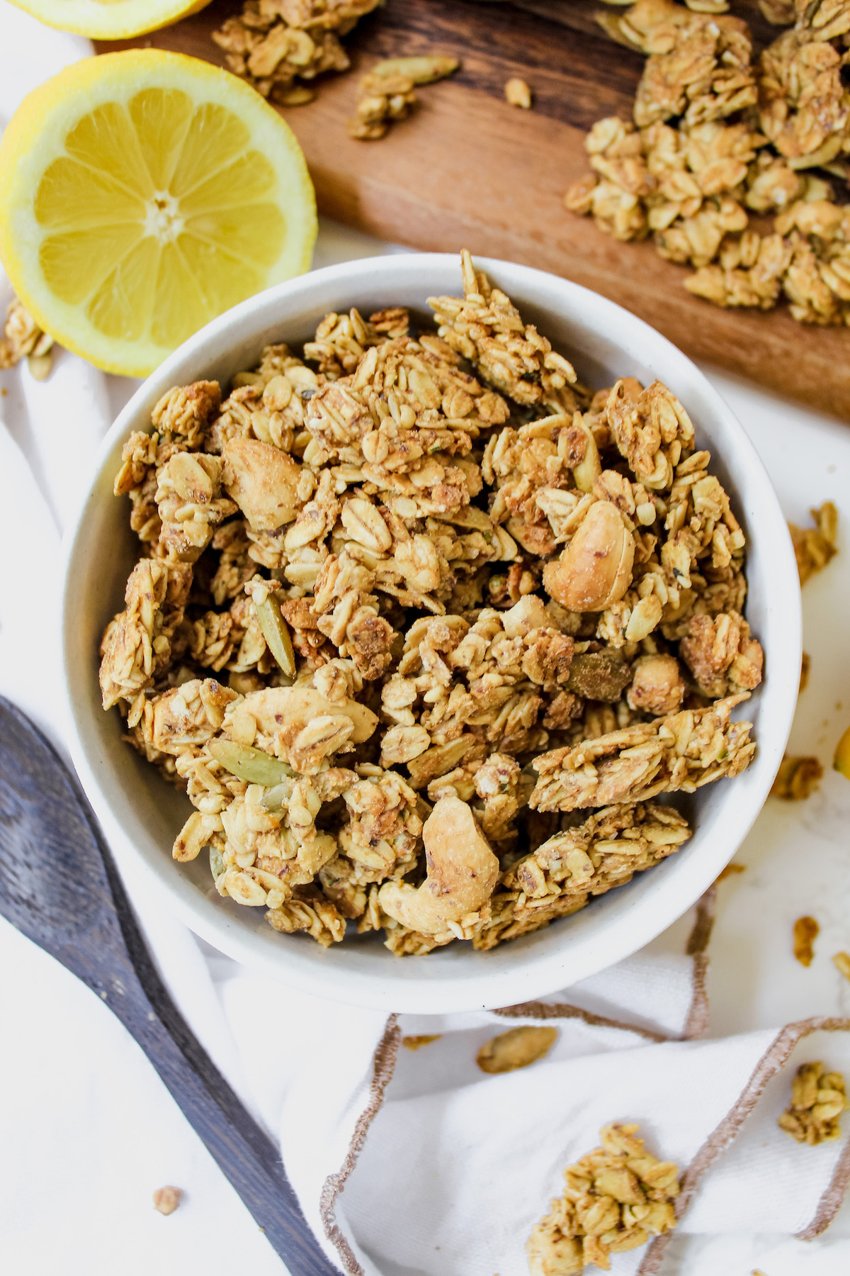 overview shot of bowl of granola with lemon slices on the side and granola on the sides