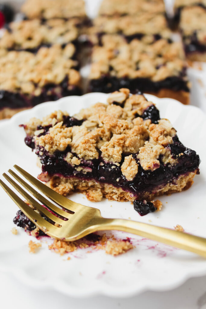 berry crumble bar on a plate with a bite taken out of it and a gold fork