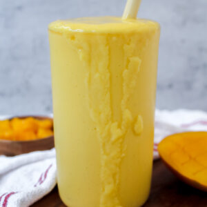 side view of a glass of coconut mango lassi with some dripping down the side