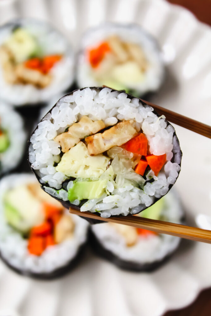 chopsticks holding a sushi roll 