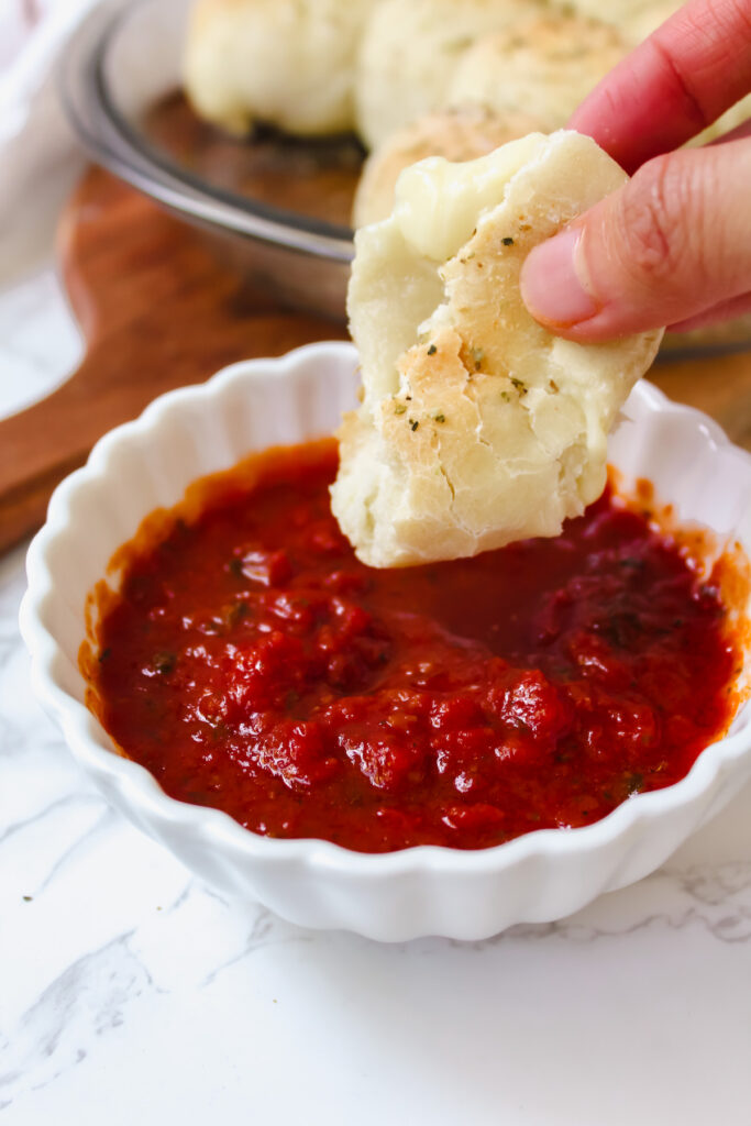 part of a pizza bite being dipped in marinara sauce