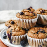 side view of the muffins stacked on a plate set on a wooden board