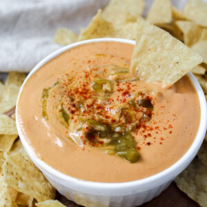 angled shot of the best vegan queso with a chip dipped in it