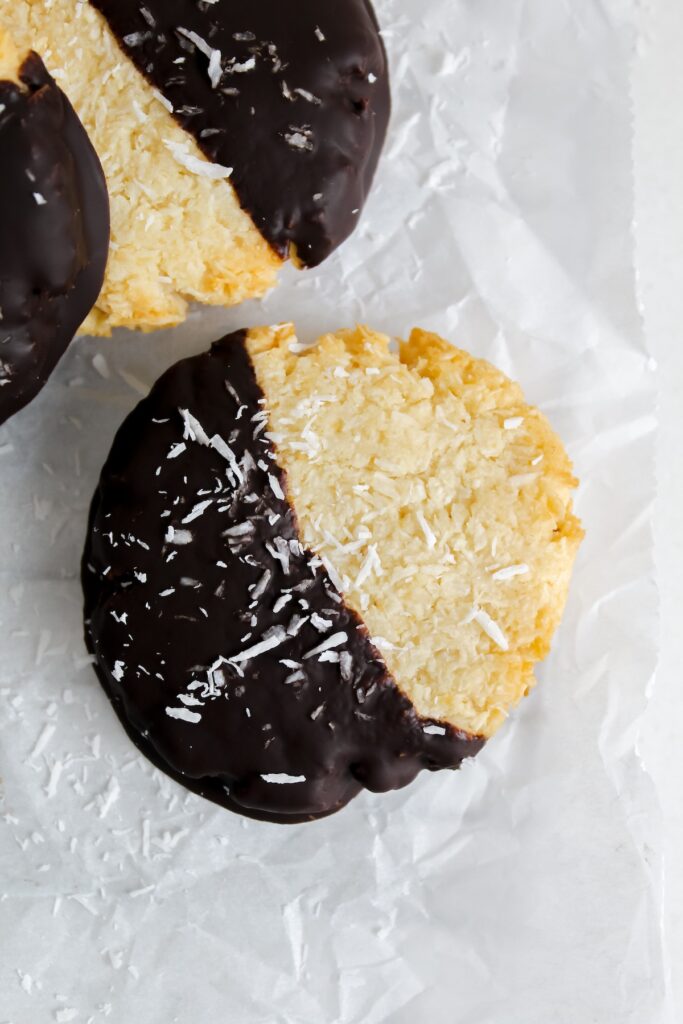 a close up shot of one chocolate dipped coconut cookie