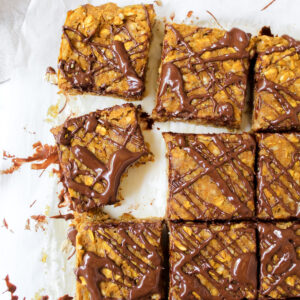 shot of sliced oatmeal bars with chocolate drizzled on top and a bite taken out of a slice