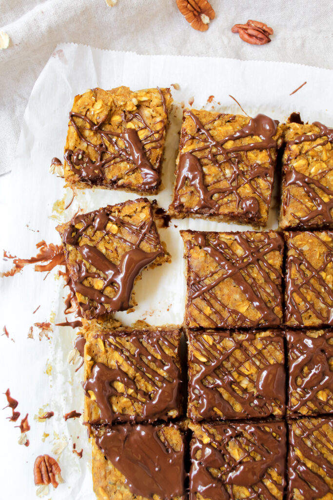 shot of sliced oatmeal breakfast bars with chocolate drizzled on top and a bite taken out of a slice