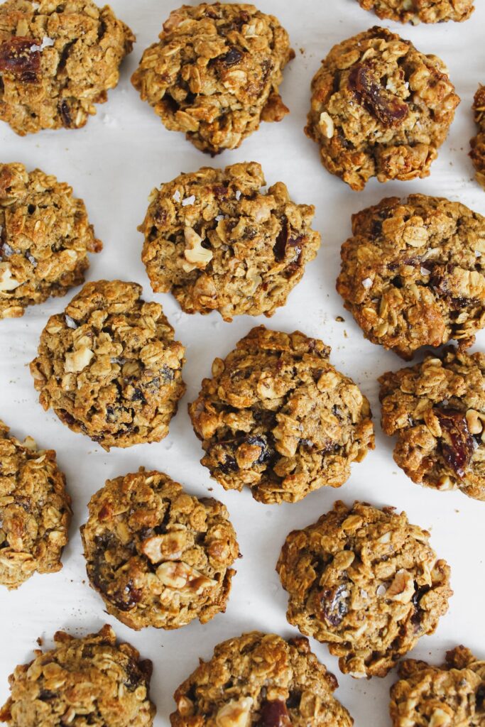 overview shot of a bunch of oatmeal date walnut cookies on a pan