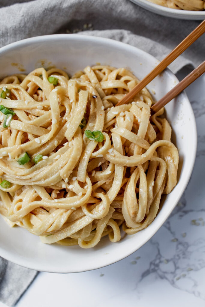 close up of sesame noodles with chopsticks in it