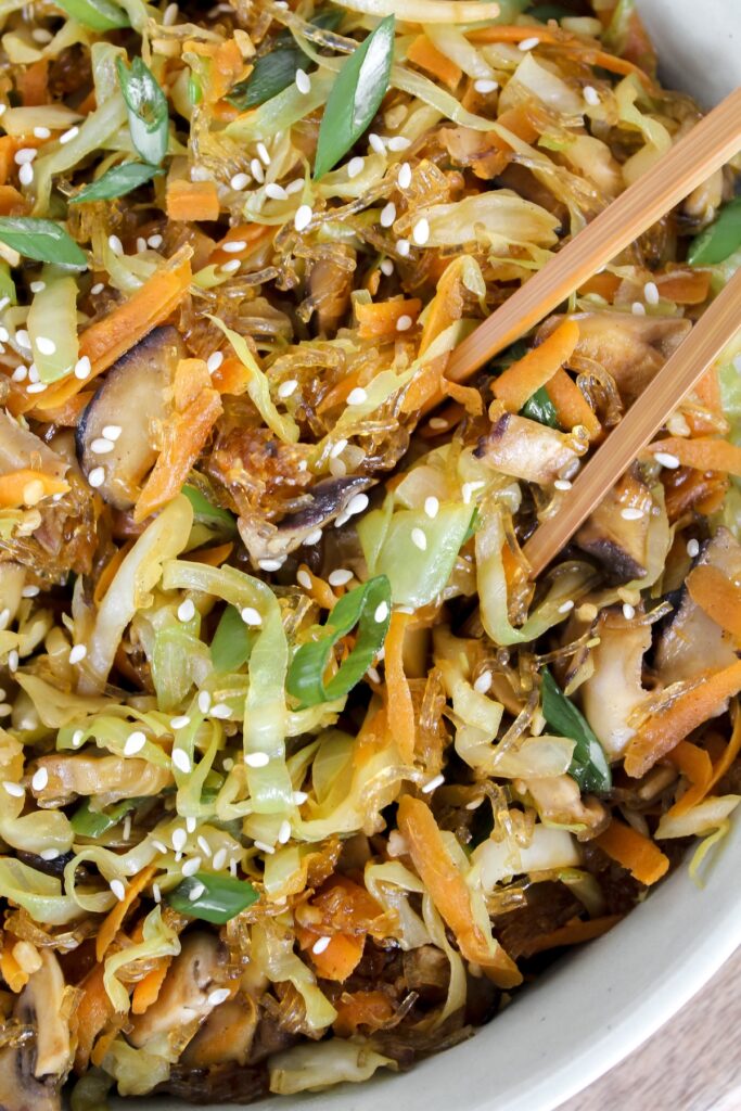 close up shot of egg roll in a bowl with chopsticks in it