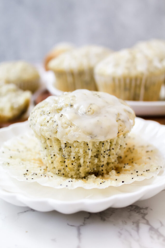 bakery style vegan lemon poppy seed muffin on a plate with the wrapper off