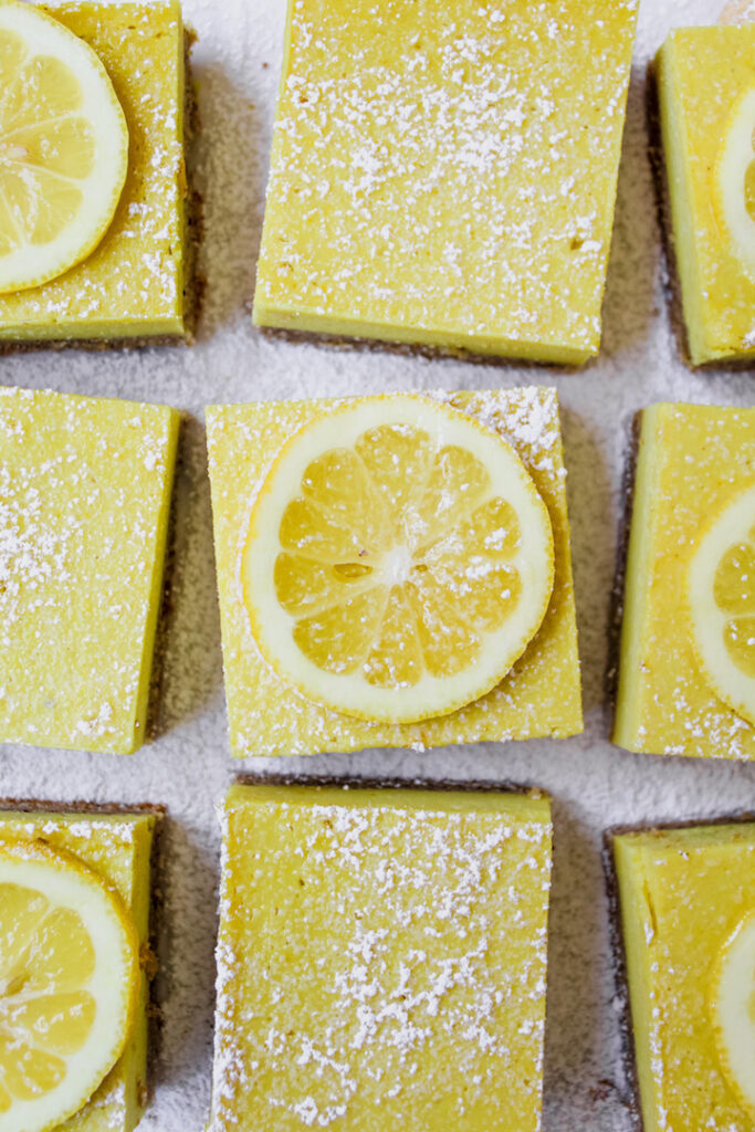 close up over lemon bars with a lemon slice on a bar