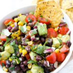 picture of a chip in a bowl of black bean corn avocado salad