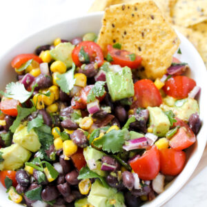 picture of a chip in a bowl of black bean corn avocado salad