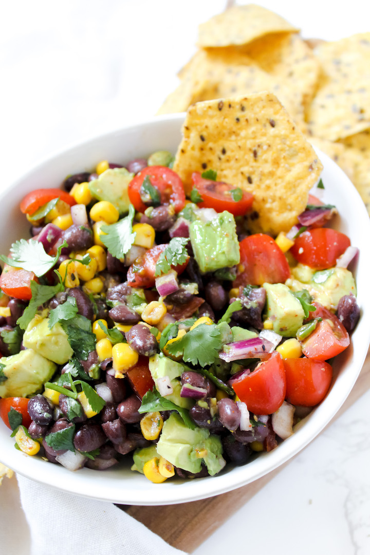 picture of a chip in a bowl of black bean corn avocado salad