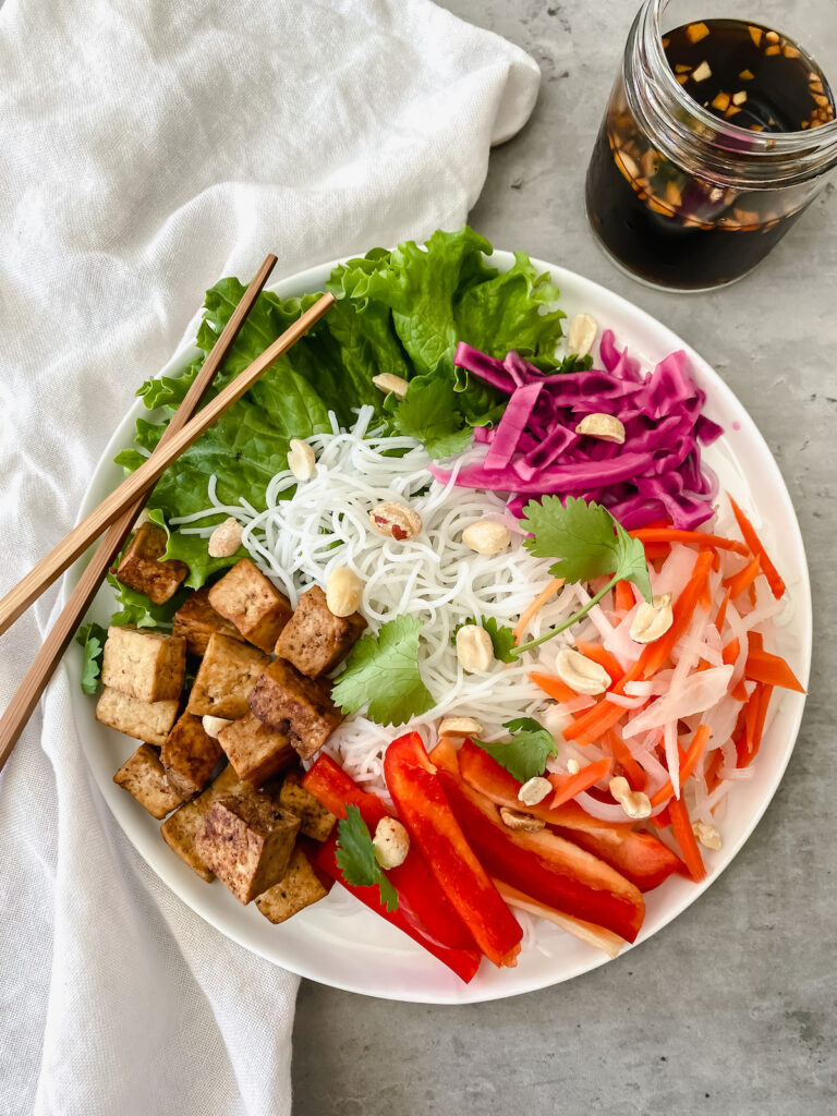 overview shot of vermicelli tofu bowl with dressing on the side