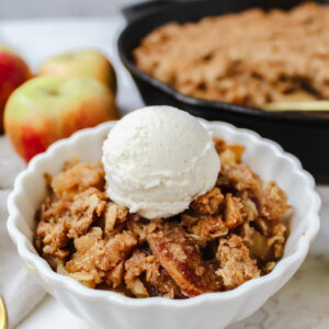 angled shot of a bowl of apple crisp with ice cream on top