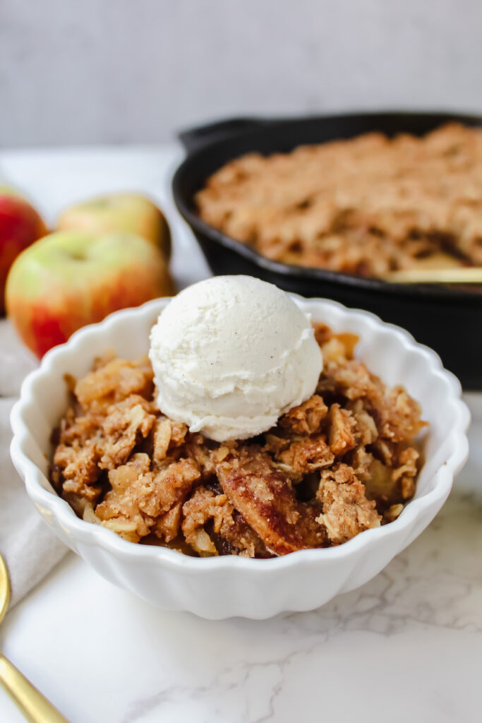 angled shot of a bowl of apple crisp with ice cream on top